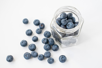 Few blueberries with glass jar. Isolated on grey background.