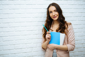 businesswoman standing near white brick wall