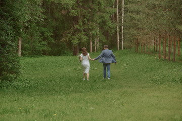 Naklejka na ściany i meble happy bride and groom run in the park