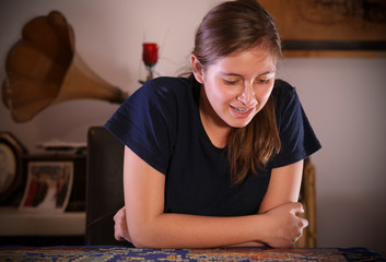 teenager smiling and playing with a puzzle at home, smiling attitude turns towards the camera and shows his happiness