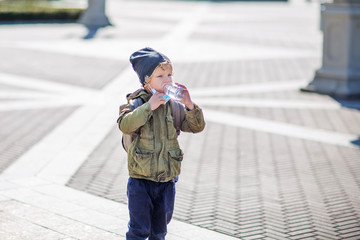 A boy in mask holds a bottle of water in hand