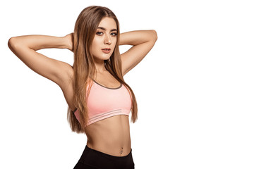 Naklejka premium Beautiful young woman in sportswear standing on a white isolated background. Keep your hands in the castle behind your head. Warm up, stretching. Tightened body. Fitness model. Pose. Copy space.