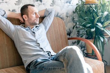 young man resting on the couch with his hands behind his head