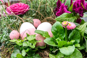 Easter arrangement with spring flowers, colorful eggs in a decorative nest.