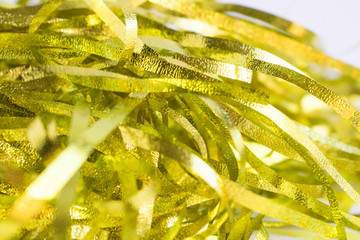 Surface covered with the golden tinsel garland as an abstract background texture. Bokeh effect.
