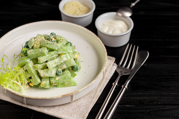 Salad of fresh cucumbers, spinach leaves, arugula, avocado. Served with slices of eggs and red pepper. Dietary nutrition. Breakfast for the whole family. Vitamin plate. On a dark wooden background.