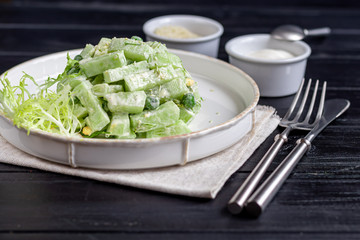 Salad of fresh cucumbers, spinach leaves, arugula, avocado. Served with slices of eggs and red pepper. Dietary nutrition. Breakfast for the whole family. Vitamin plate. On a dark wooden background.