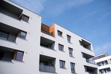 Fototapeta premium Exterior of new apartment buildings on a blue cloudy sky background. No people. Real estate business concept.