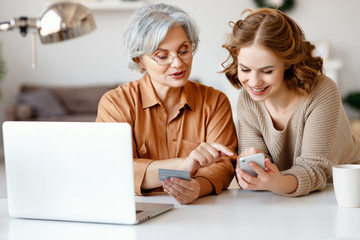 Young woman teaching grandmother to do online shopping.