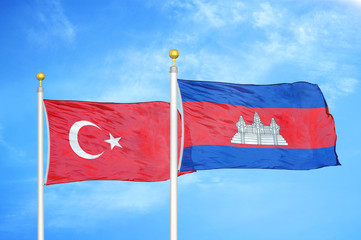 Turkey and Cambodia two flags on flagpoles and blue cloudy sky