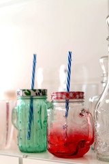 Glass mugs with tubes. Transparent cups of red and green color with a lid.