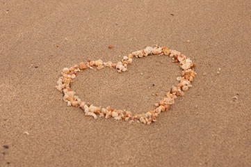 The shape of heart made from small shells on the sand beach, selective focus