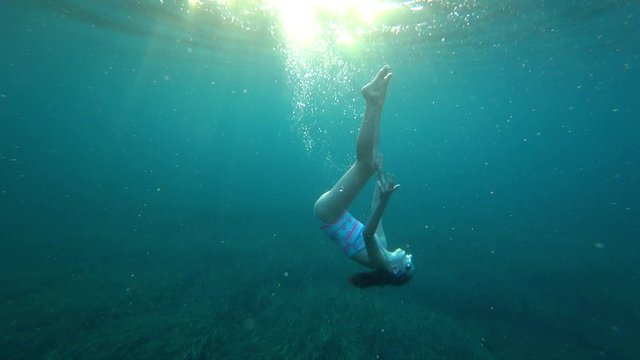 Young girl snorkeling underwater in deep blue sea with air bubbles