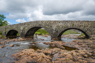 Fototapeta na wymiar Mountain river and vintage bridge at Island of Skye, Hebrides archipelago, Scotland.