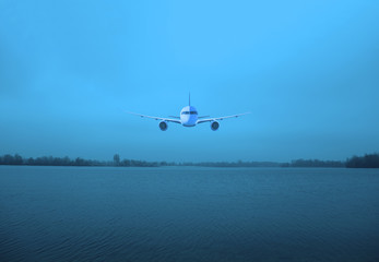 A wide landscape of a dark gray lake and forest. Overcast sky