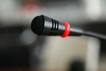 Close-up of small black microphone for public speaking on blurred backdrop. Seminar room or conference. Performance on stage. Lecture for auditorium concept