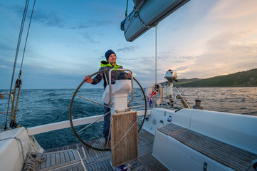 Sailboat helmsman at his watch with beautiful sunset near Campbeltown, Scotland - obrazy, fototapety, plakaty