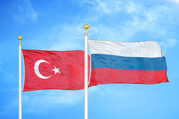 Turkey and Russia two flags on flagpoles and blue cloudy sky