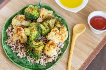 Baked broccoli and cauliflower. Vegetables with rice and spices on plate close up. Vegan healthy diet food concept