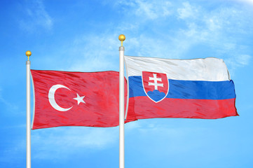 Turkey and Slovakia two flags on flagpoles and blue cloudy sky
