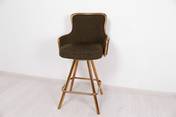 green bar stool with soft upholstery and gold legs on a white background