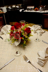Mesa con copas, cubiertos servilletas y rosas rojas