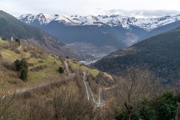 Views of the church of Mont and Vielha town from Montcorbau with snowy mountains in the background.