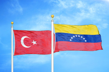 Turkey and Venezuela two flags on flagpoles and blue cloudy sky