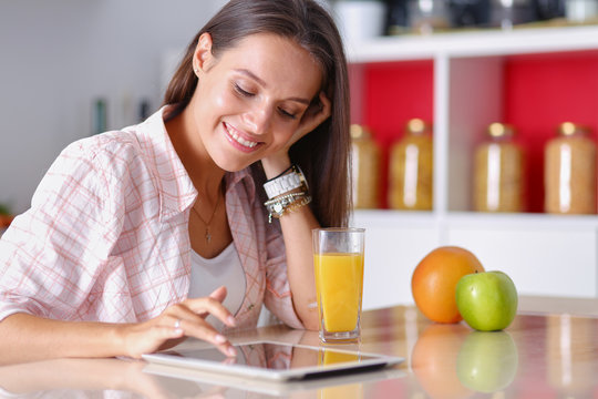 Young Woman In The Kitchen, Using Her Ipad. Young Woman