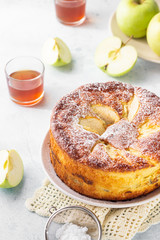 Delicious apple pie or sponge cake decorated with powdered sugar. Morning atmospheric lighting, trendy soft shadows, selective focus. Charlotte with apples. 