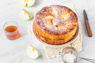Delicious apple pie or sponge cake decorated with powdered sugar. Morning atmospheric lighting, trendy soft shadows, selective focus. Charlotte with apples. 