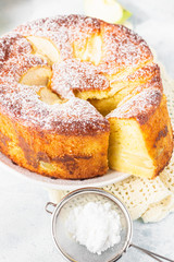 Piece of charlotte with apples. Delicious apple pie or sponge cake decorated with powdered sugar. Morning atmospheric lighting, trendy soft shadows, selective focus. 