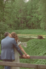 young couple kiss on a wooden bridge