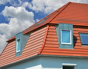 Sattelgaube mit Stehfalz-Metallverkleidung als Wetterschutz an einem Ziegeldach