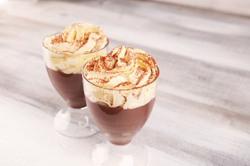 Hot chocolate cocoa in glas cup with whipped cream on vintage background