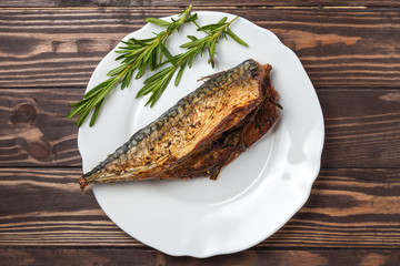 Roasted mackerel with rosemary. in a white plate on a wooden countertop. close-up