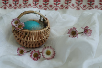 Easter basket with daisies on the background of embroidery