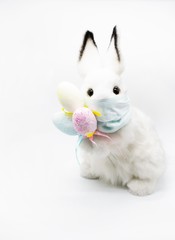 Easter Bunny in a facial medical mask with a bouquet of colorful eggs. The concept of Easter and quarantine during coronavirus. Like a postcard wishing you well