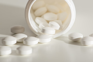 Fototapeta na wymiar Spilled white medicine pile of prescription pills in a white bottle on a white background