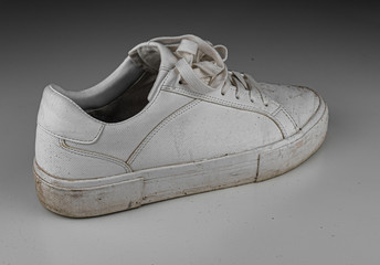 Dirty, used, muddy white right shoes on white dirty floor