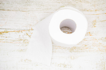 Roll of white toilet paper with perforation on aged light wood background