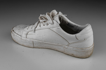 Dirty, used, muddy white right shoes on white dirty floor