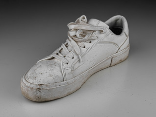 Dirty, used, muddy white right shoes on white dirty floor