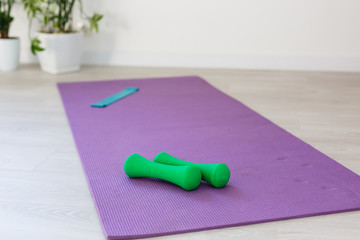 Unrolled yoga mat on wooden floor in modern fitness center or at home with big windows and white brick walls, comfortable space for doing sport exercises, meditating, yoga equipment