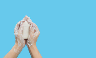 Hand hygiene concept. Female hands are holding antibacterial soap with foam on a blue background. Hand antiseptic during the coronovirus pandemic