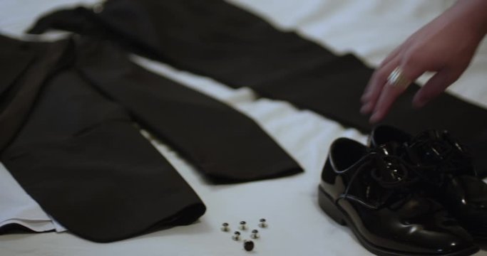 Black man picks up shoes from bed