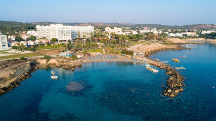 Naklejka na ściany i meble Aerial bird's eye view of Green bay in Protaras, Paralimni, Famagusta, Cyprus. Famous tourist attraction diving location rocky beach with boats, sunbeds, sea restaurants, water sports from above.