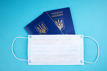 Ukrainian passport with face mask on it over blue background. copy space. covid-19 travel and tourism concept.