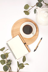 Cup coffee, pencil, branch with leaf, paper note on white background.