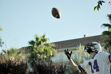 American football player in a game. Player catching an American football ball in a park.